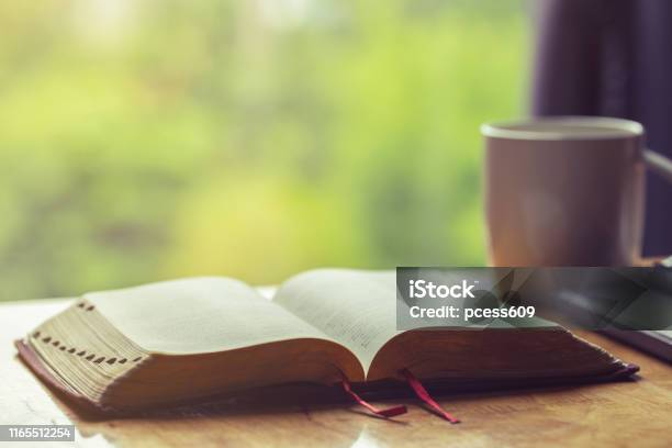 Open Bible With A Cup Of Coffee For Morning Devotion On Wooden Table With Window Light Stock Photo - Download Image Now