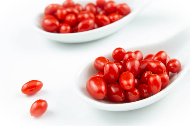 fresh goji berries in small white porcelain spoons isolated on white copy space closeup