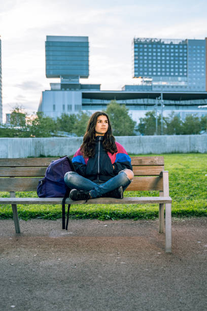 istock Casual student waiting, sitting on a bench at the campus 1165512652