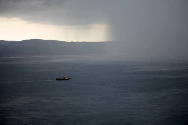 Summer storm reaches a ship at sea in front of an island