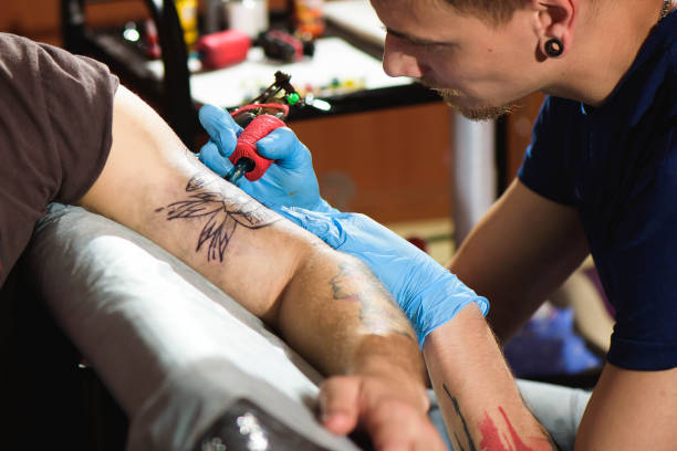 istock Professional tattoo artist makes a tattoo on a man's hand. 1165515834
