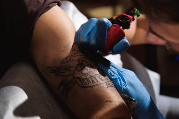 istock Professional tattoo artist makes a tattoo on a man's hand. 1165515851
