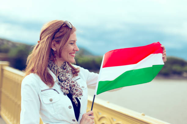 istock Happy young woman stretching Hungarian flag on bridge 1165517048
