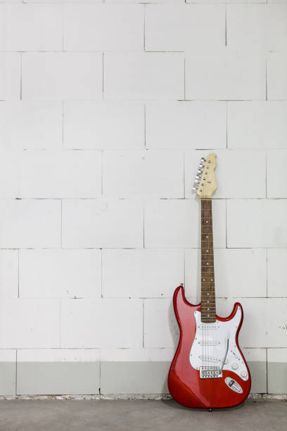 istock Red electric guitar stands on the right against white brick wall 1165518444