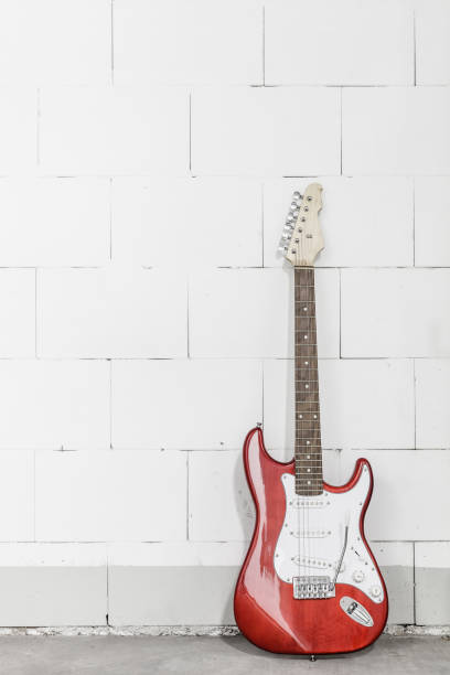 istock Red electric guitar stands on the right against white brick wall 1165518455
