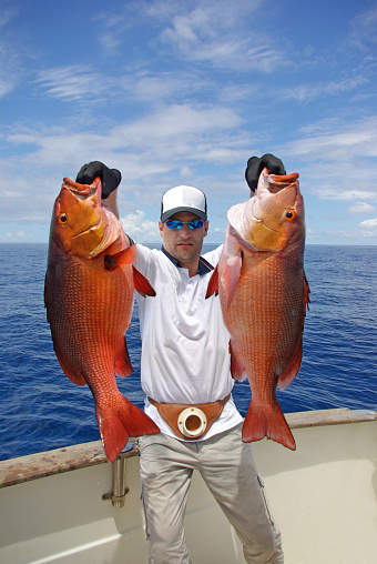 Deep sea fishing, boat fishing, tropical fishing, big game fishing. lucky fisherman holding a big snapper fish