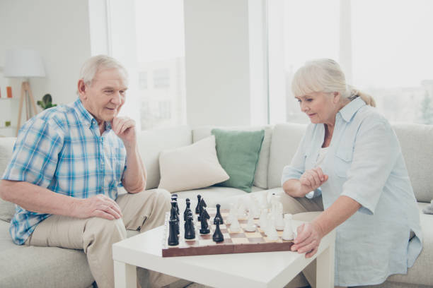 istock Profile side view portrait of her she his he two nice attractive cheerful focused smart clever people playing chess spending free time in light white interior living-room house 1165520339