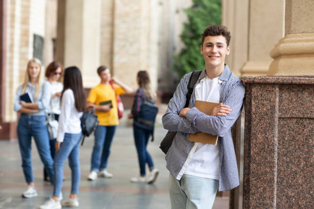 istock University life. Happy guy holding books and smiling 1165524466