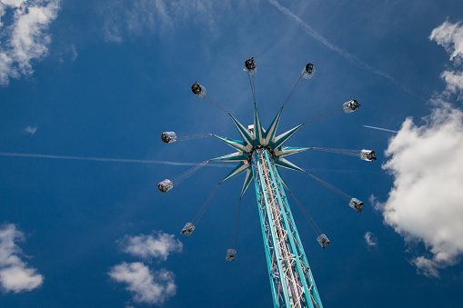 Amusement ride at chairoplane with flying people in front of a blue and cloudy sky
