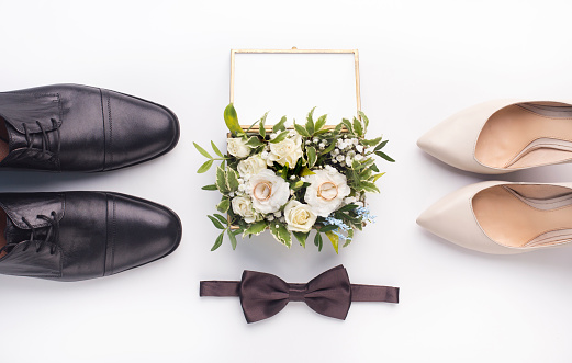 Bride and groom accessories. Wedding shoes, bow-tie and bouquet on white background, panorama