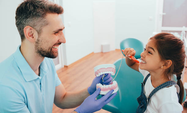 bambina che ride mostrando come lavarsi i denti dal suo dentista, durante un appuntamento dentale - healthy lifestyle human teeth adult brushing foto e immagini stock