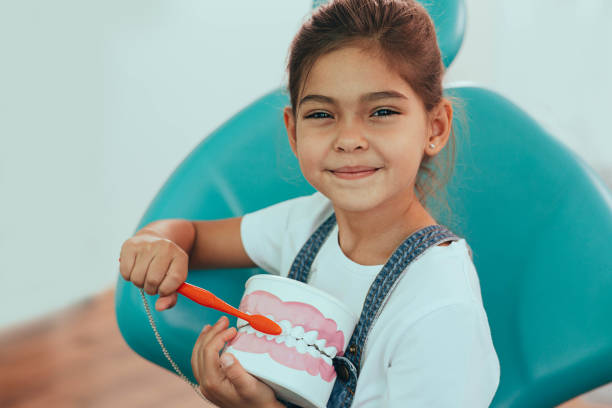 istock Mixed race girl brushing teeth. Child holding teeth model and showing how brushing teeth 1165526819