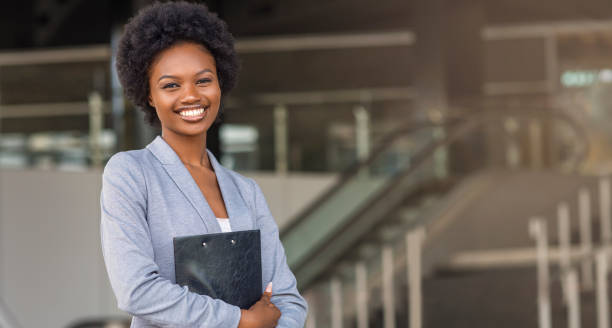istock Beautiful Afro business woman holding a folder, looking at camera 1165528212
