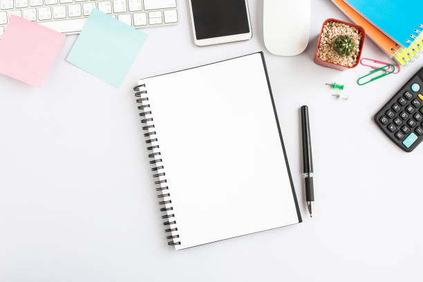 istock Top view, empty notebook and office supplies on the desk. 1165528459