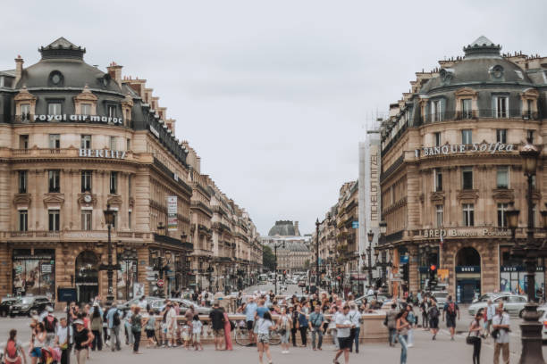 PARIS, FRANCE - JULY 19th, 2014. A view down Avenue de l'Opera busy with pedestrians and traffic on a summer day with high clouds. PARIS, FRANCE - JULY 19th, 2014. A view down Avenue de l'Opera busy with pedestrians and traffic on a summer day with high clouds. Cloudy weather place de lopera stock pictures, royalty-free photos & images