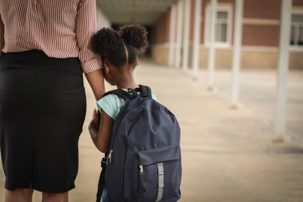 elementare, ragazza afroamericana con mamma il primo giorno di scuola. - ansia foto e immagini stock