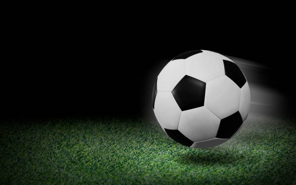 istock Soccer ball on green grass and black background 1165536866