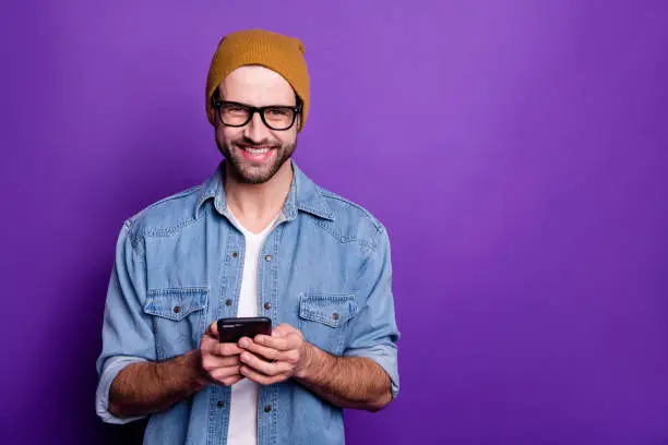 Cool handsome guy holding, telephone writing friends casual denim outfit isolated violet background