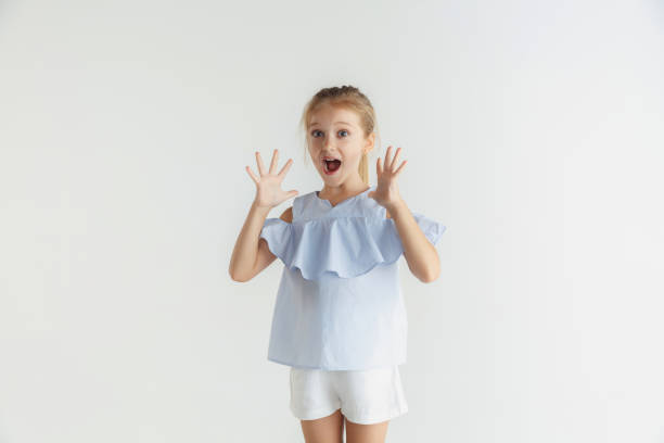 istock Little smiling girl posing in casual clothes on white studio background 1165540748