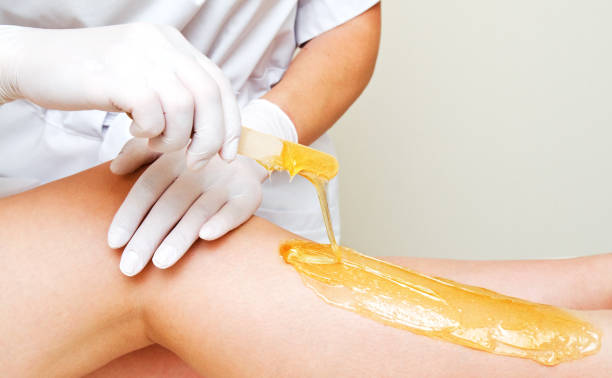 cosmetologist beautician depilar las piernas femeninas en el salón de belleza del centro de spa - leg waxing fotografías e imágenes de stock