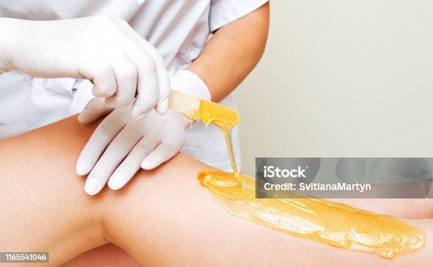 Cosmetologist Beautician Waxing Female Legs In The Spa Center Beauty Salon Stock Photo - Download Image Now