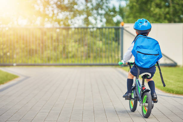 istock School boy in safety helmet riding bike with backpack 1165550003