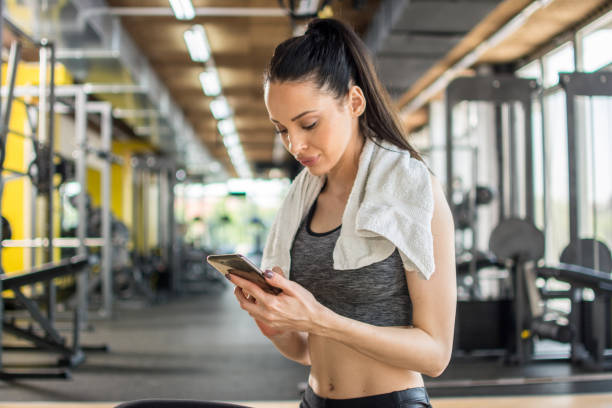istock Young sportive woman using phone after training in gym 1165550011