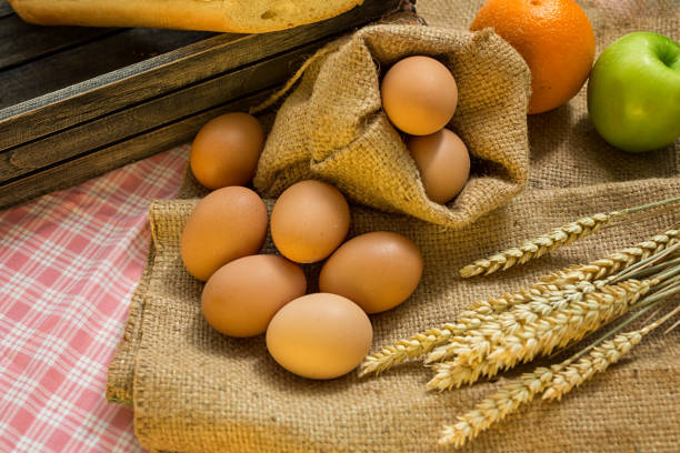 istock breakfast and baked bread concept. Fresh fragrant bread and egg and apple on the fabric sack. On wooden table. 1165555034