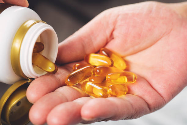 staruszka wylewająca kapsułki oleju rybnego z butelki, z bliska - fish oil vitamin e cod liver oil nutritional supplement zdjęcia i obrazy z banku zdjęć