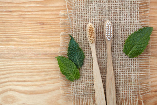 istock Zero waste concept. Bamboo toothbrush on wooden background with green mint leaf. Plastic free essentials, teeth care. 1165563697