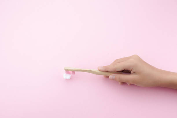 istock child's hand with toothbrush and white platic tooth on pink background 1165563918