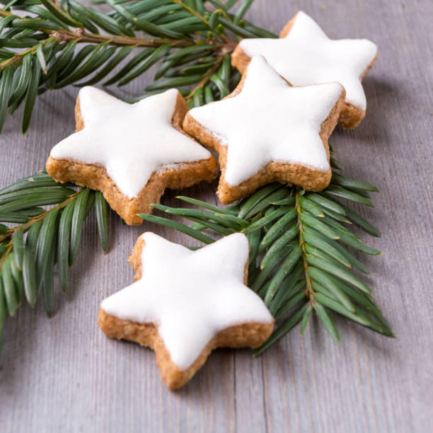 cinnamon star cookies lying on conifer branch and wooden board