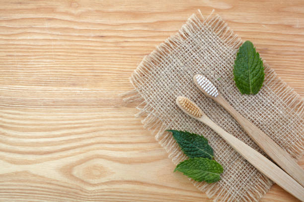 istock Zero waste concept. Bamboo toothbrush on wooden background with green mint leaf. Plastic free essentials, teeth care. 1165564767