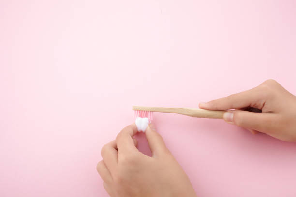istock child's hand with toothbrush and white platic tooth on pink background 1165564840
