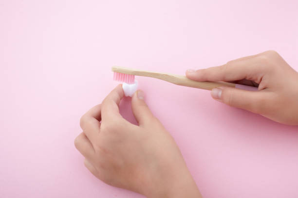 istock child's hand with toothbrush and white platic tooth on pink background 1165564915