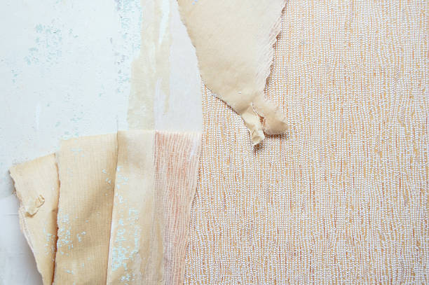 istock Ragged beige wallpaper on the wall. Close-up. 1165569258