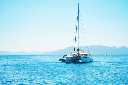 Sailing yacht catamaran boat in the sea in Greece, turquoise waters of Aegean Sea near Athens. Famous travel sailing destination in Europe. Sailboat.