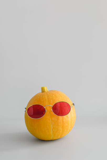 istock Juicy bright orange pumpkin in red sunglasses on a white solid background. Halloween minimal concept. Copy space. 1165572461