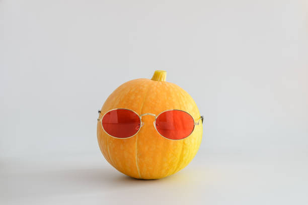 istock Juicy bright orange pumpkin in red sunglasses on a white solid background. Halloween minimal concept. Copy space. 1165573183