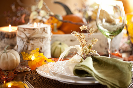 Autumn holiday Thanksgiving dining with beautiful traditional centerpiece filled with pumpkins and gourds.