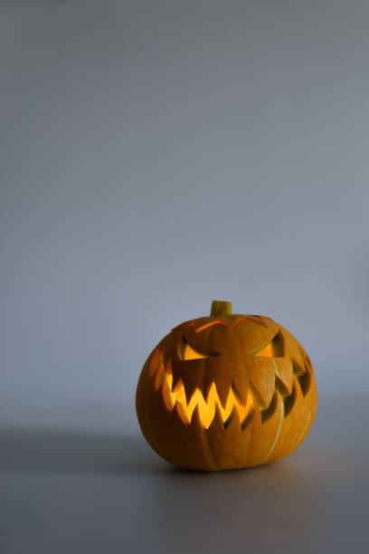istock Bright orange Jack-o'-lantern pumpkin on white solid background. Glowing eyes and a terrible grin. Halloween minimal concept. Copy space. 1165573639