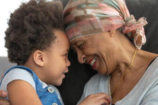 старшая женщина с раком любовно обнимает внучку - grandmother child grandparent hope стоковые фото и изображения