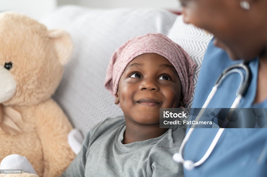 Улыбающийся мальчик с раком утешил женщина-врач африканского происхождения - Стоковые фото Ребёнок роялти-фри