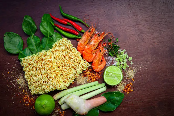 Photo of Instant noodles,Instant noodles, shrimp soup,ant noodle,Ingredients for popular Thai soup Tom-yum kung. Lime, galangal, red chili, cherry tomato, lemongrass and kaffir lime leaf on black board . Flat lay