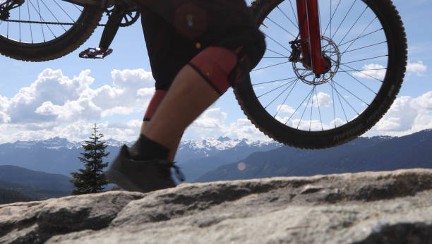 istock Mountain biker carries bikes over rocky terrain 1165583266
