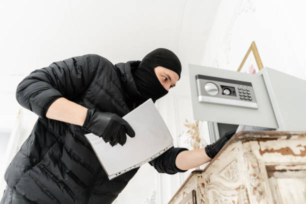 the thief opens the electronic safe. the burglar commits a crime in luxury apartment with stucco. thief with black balaclava stealing safe box. - night deposit box imagens e fotografias de stock