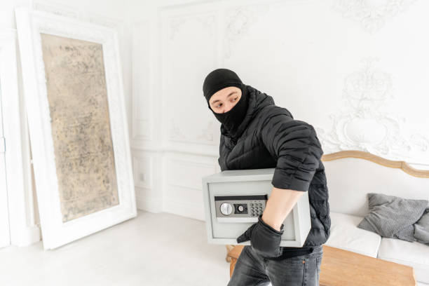 thief with black balaclava stealing modern electronic safe box. the burglar commits a crime in luxury apartment with stucco. - night deposit box imagens e fotografias de stock