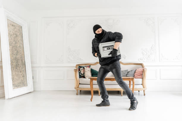 thief with black balaclava stealing modern electronic safe box. the burglar commits a crime in luxury apartment with stucco. - night deposit box imagens e fotografias de stock