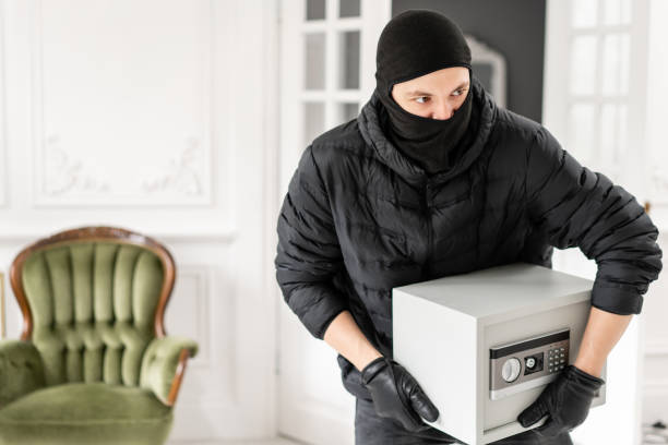 thief with black balaclava stealing modern electronic safe box. the burglar commits a crime in luxury apartment with stucco. - night deposit box imagens e fotografias de stock