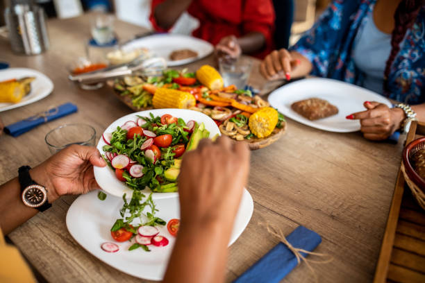 Unrecognizable person pouring fresh vegetarian salad in plate  during  healthy dinner